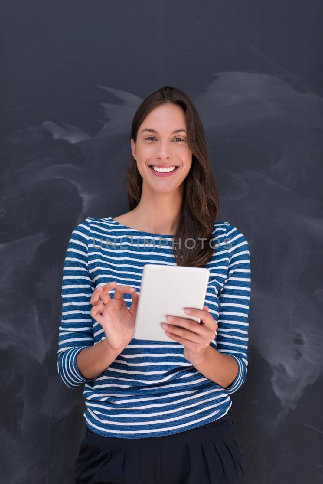 Happy young woman using tablet computer in front of chalk drawing board