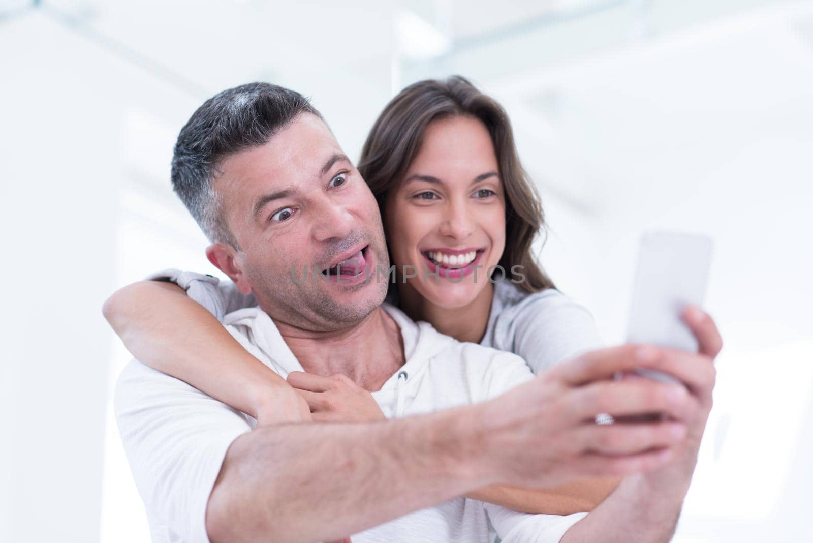 happy couple using mobile phone at home by dotshock