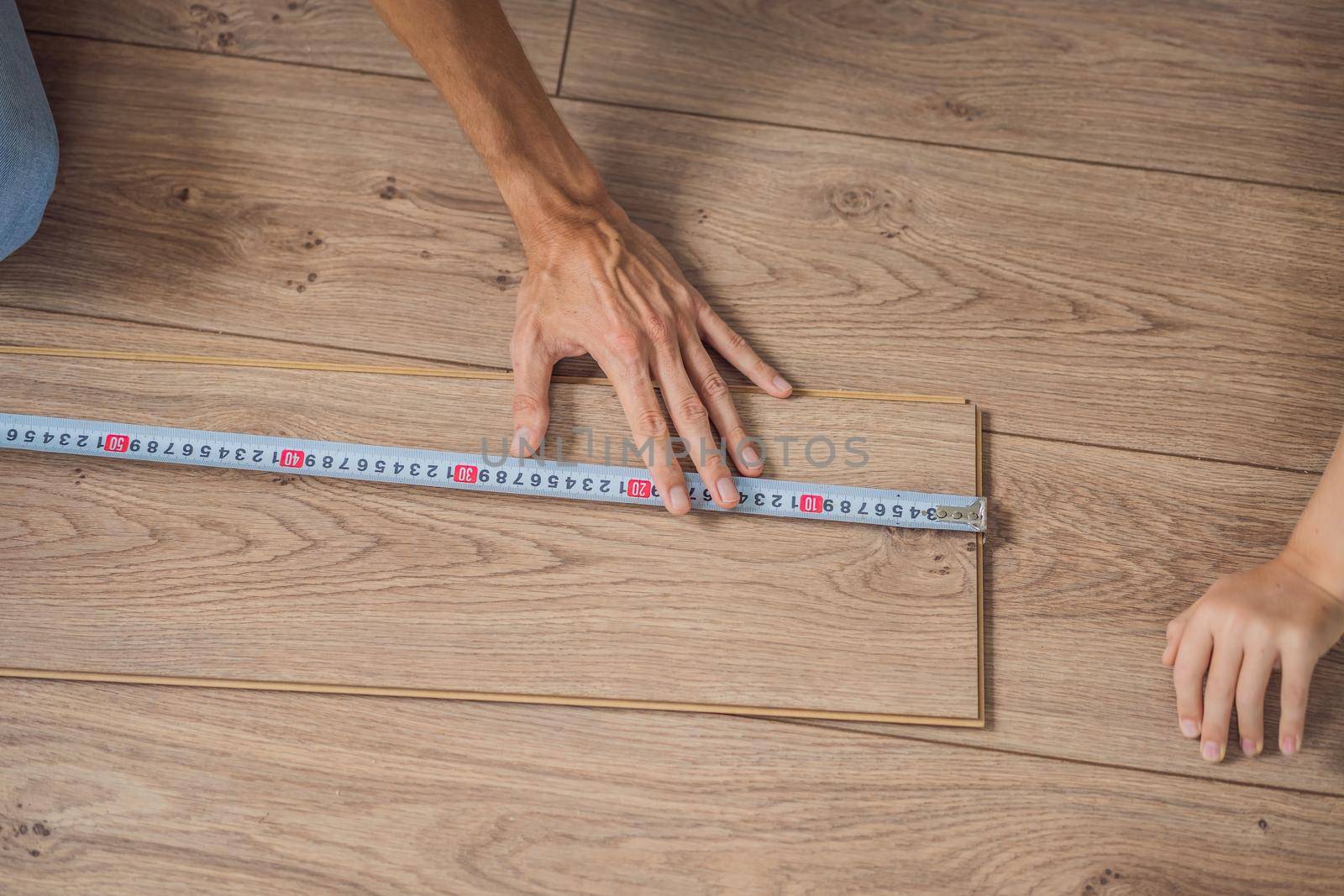 Man installing new wooden laminate flooring on a warm film floor. Infrared floor heating system under laminate floor.