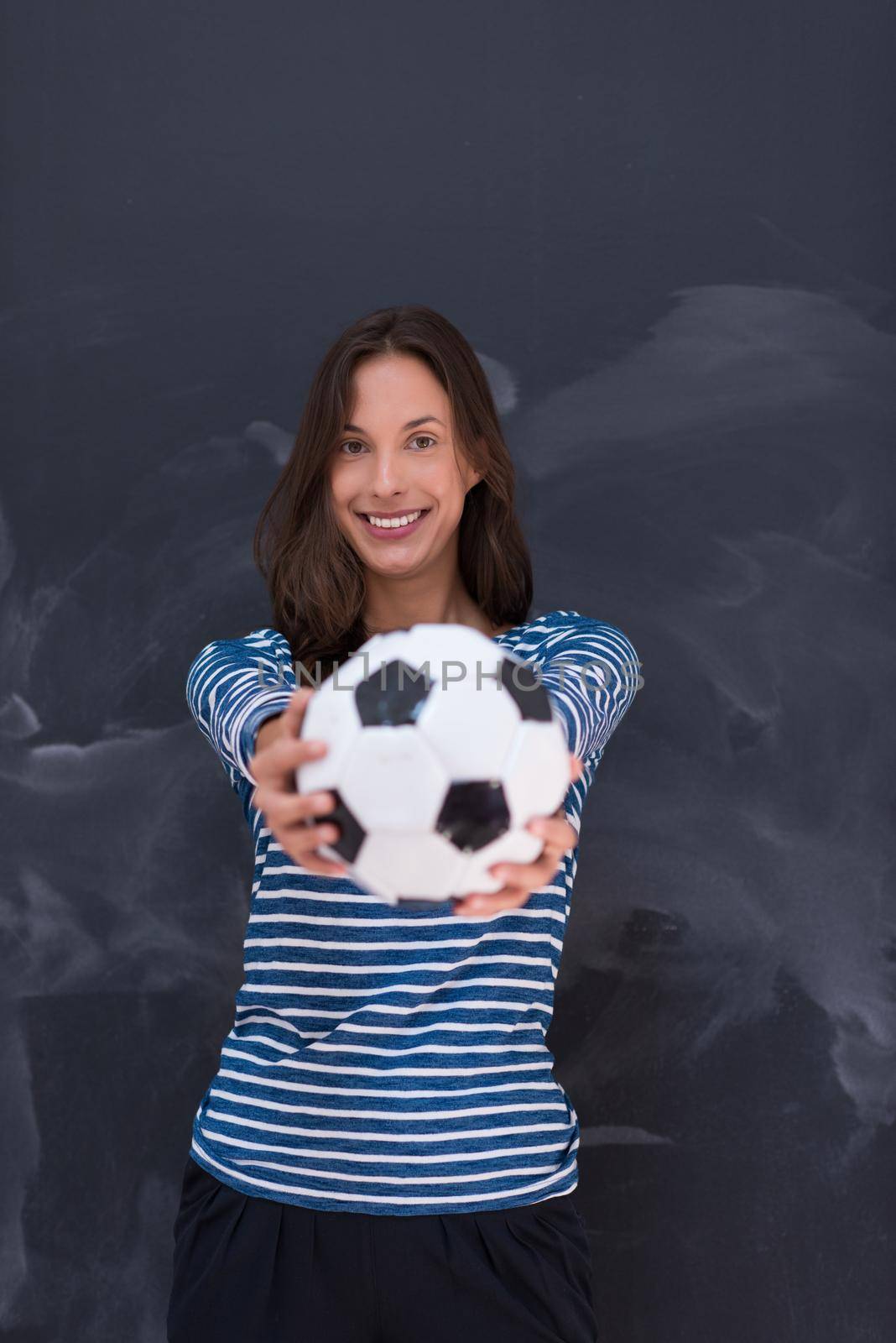 portrait of a young woman holding a soccer ball in front of chalk drawing board