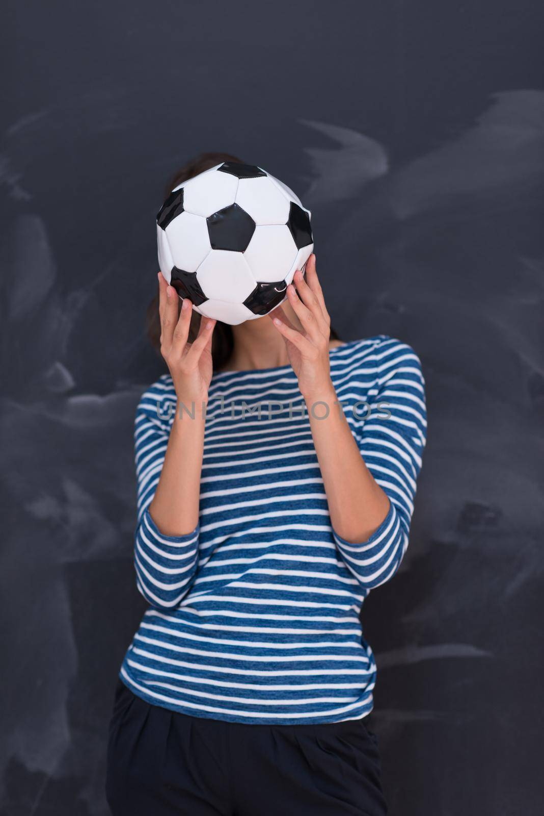 portrait of a young woman holding a soccer ball in front of chalk drawing board