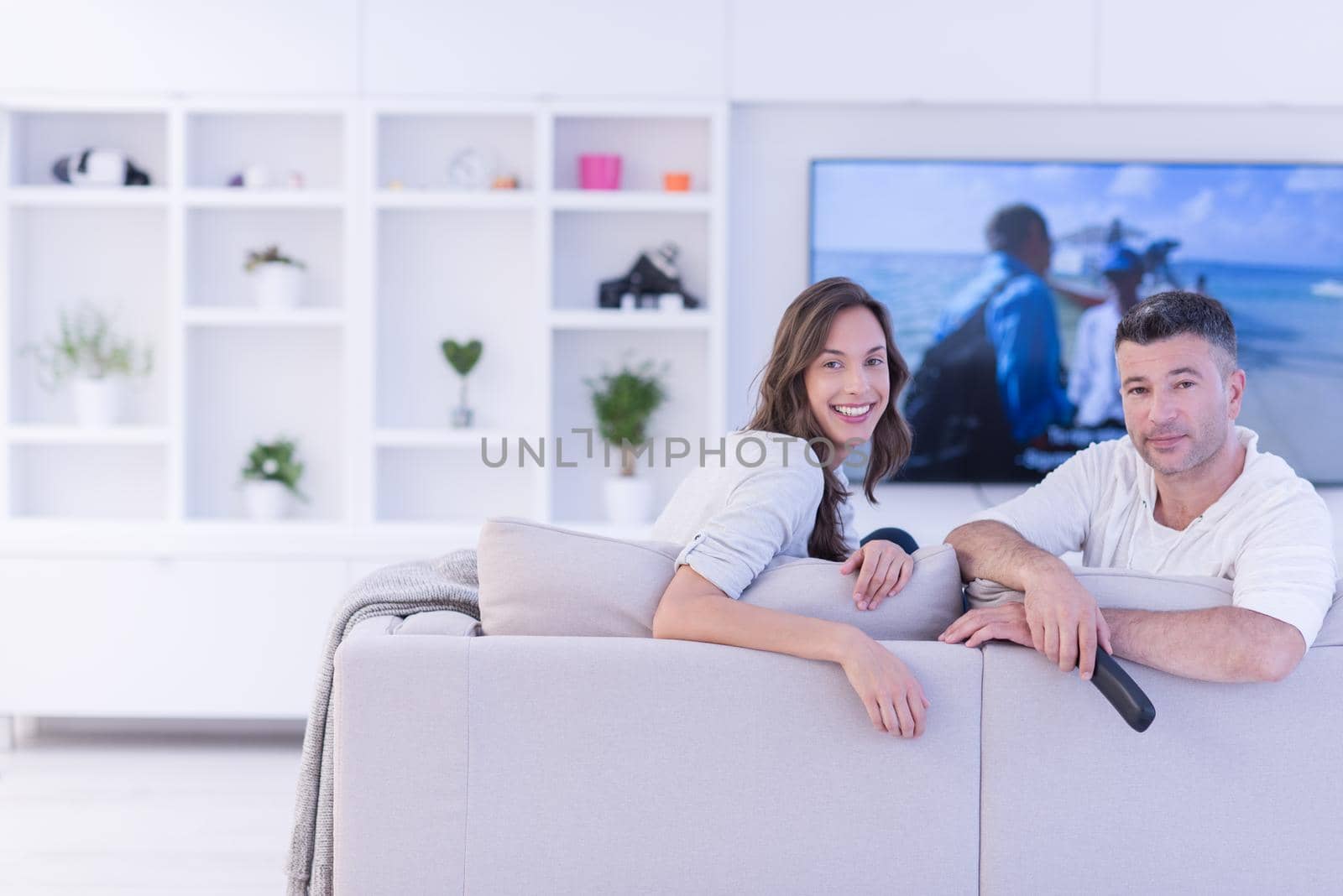 Young couple on the sofa watching television together in their luxury home