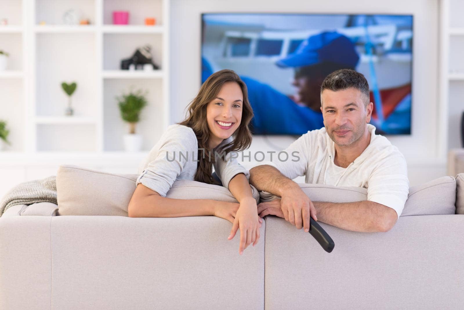 Young couple on the sofa watching television together in their luxury home