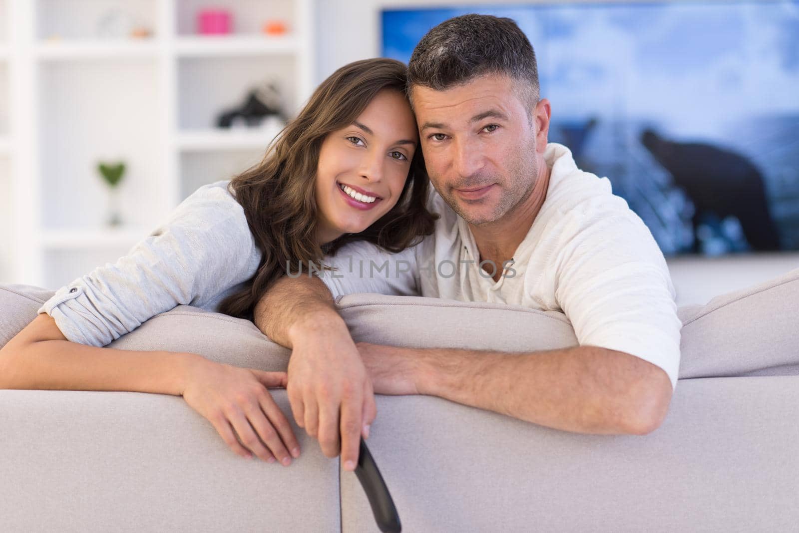 Young couple on the sofa watching television together in their luxury home