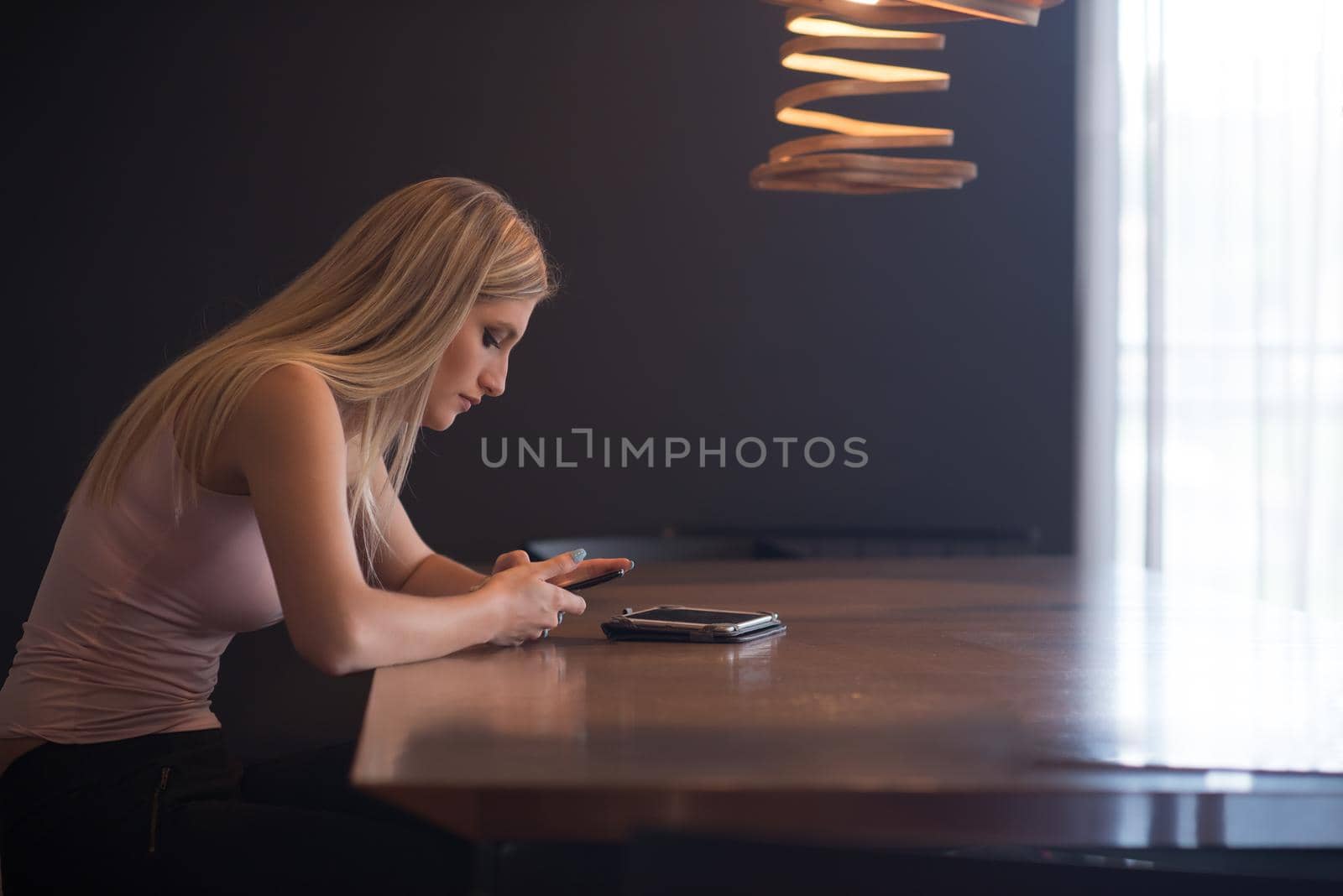 young happy woman sitting at the table and using mobile phone at luxury home