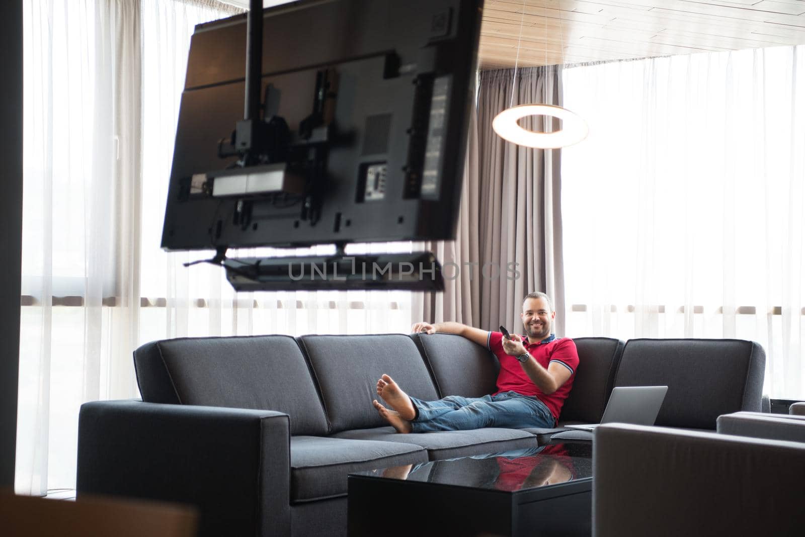 young handsome man enjoying free time watching television in his luxury home villa