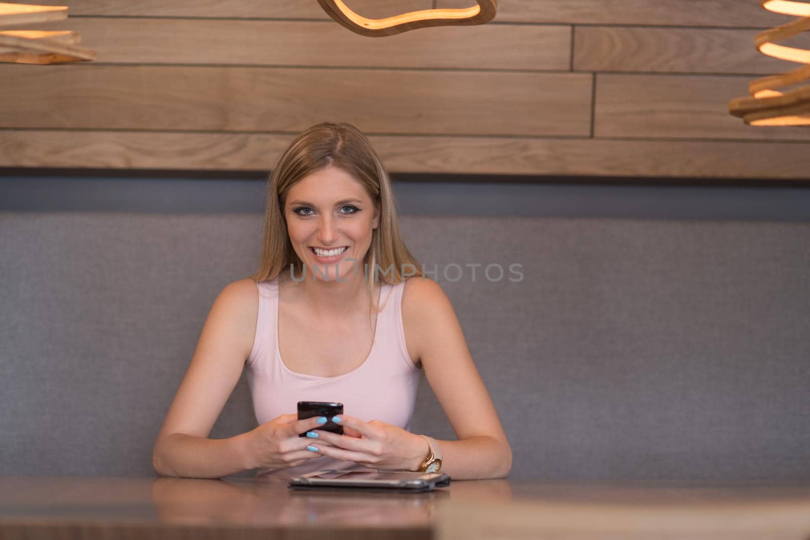 young happy woman sitting at the table and using mobile phone at luxury home