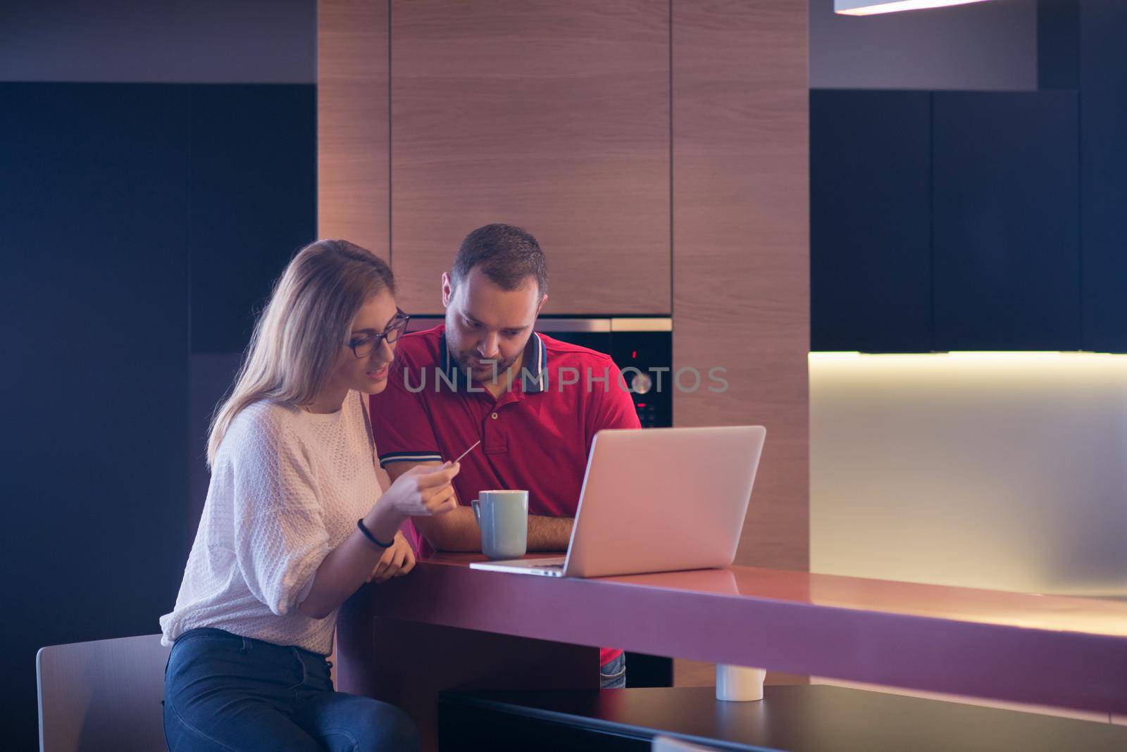 happy young couple buying online using laptop a computer and a credit card in their luxury home villa