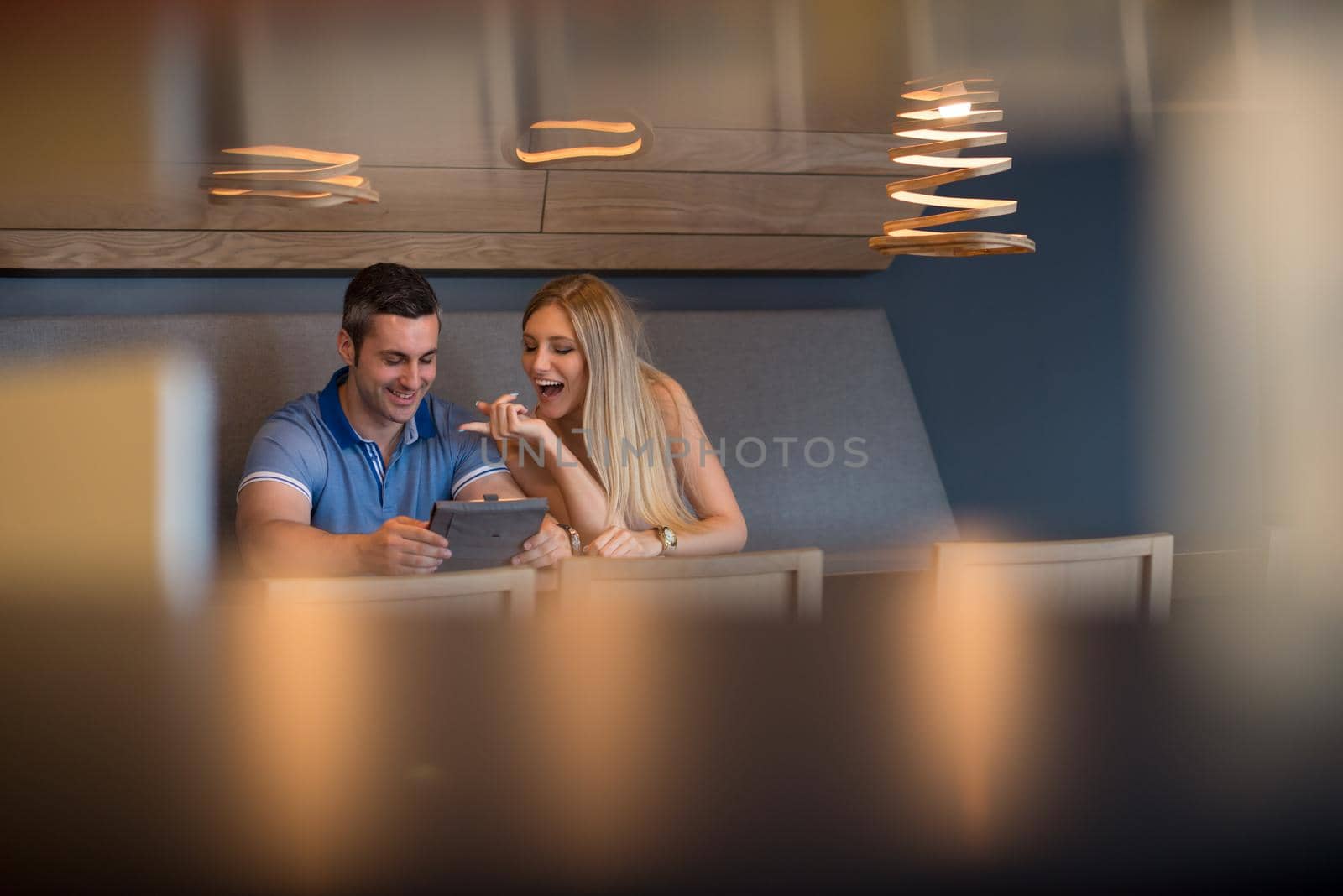 Young couple using tablet computer at luxury home together, looking at screen, smiling.