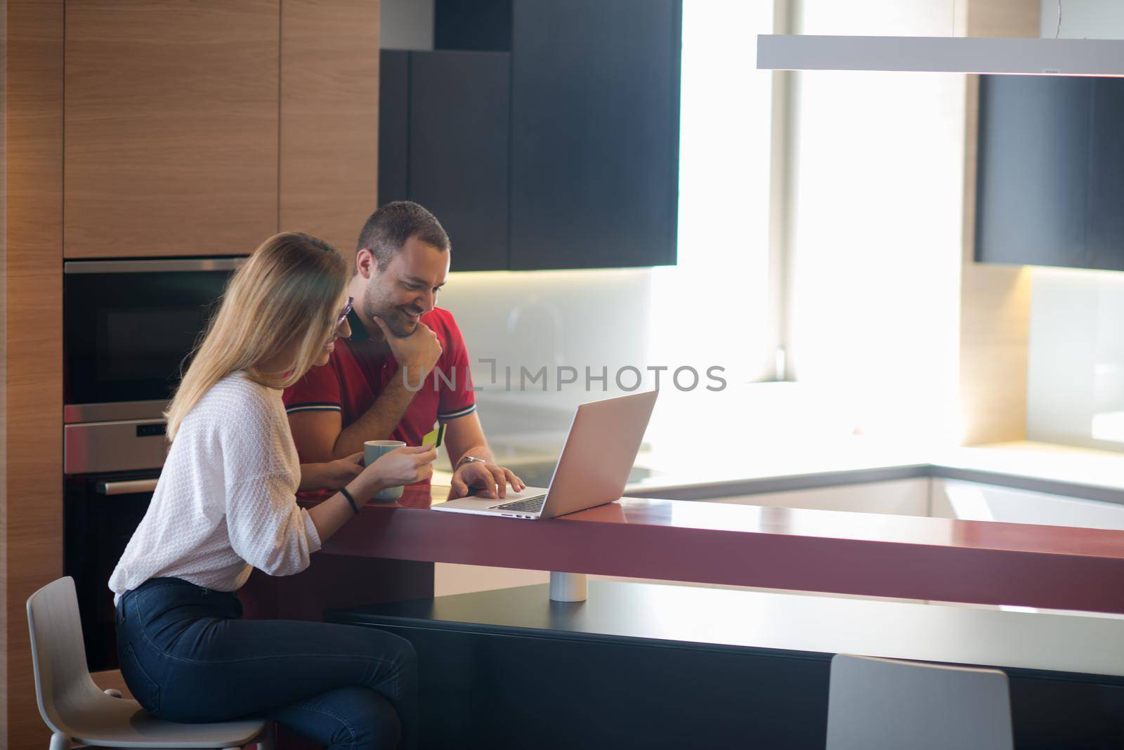 happy young couple buying online using laptop a computer and a credit card in their luxury home villa