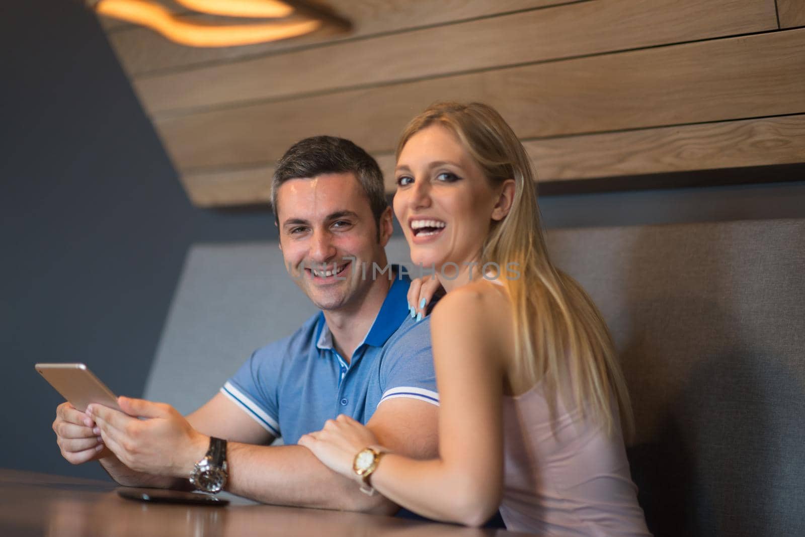 Young couple using tablet computer at luxury home together, looking at screen, smiling.