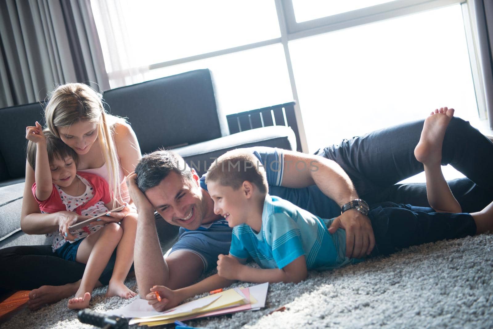 Happy Young Family Playing Together at home on the floor using a tablet and a children's drawing set