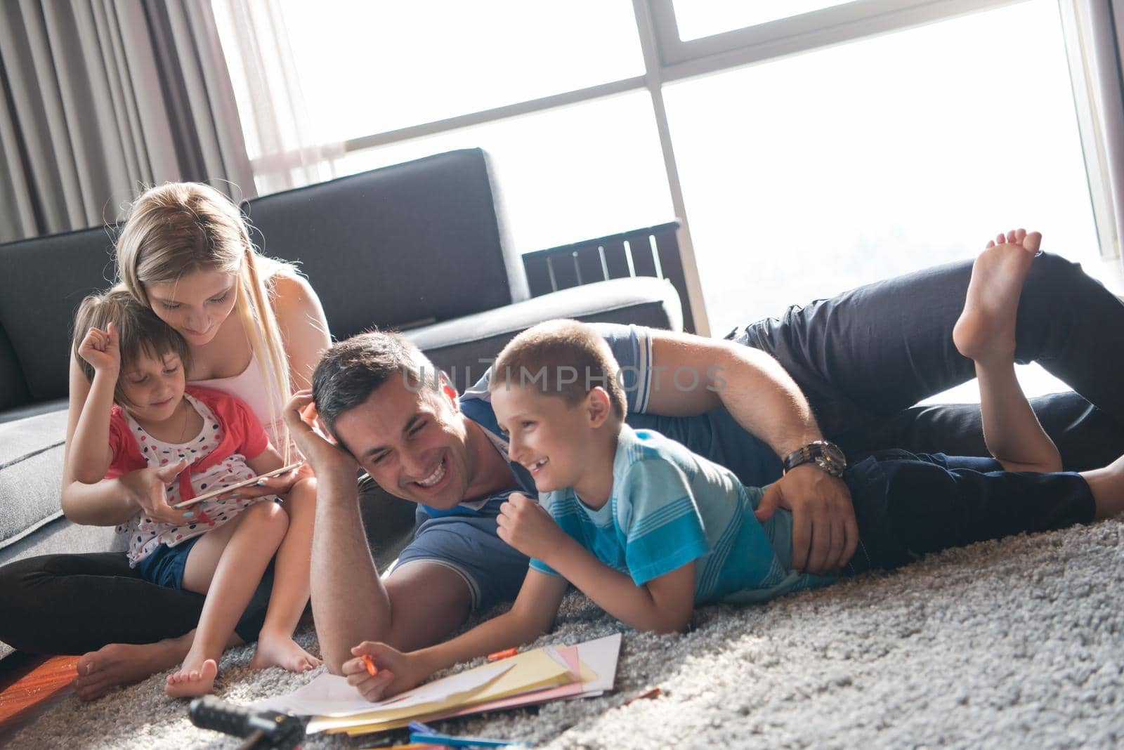 Happy Young Family Playing Together at home on the floor using a tablet and a children's drawing set