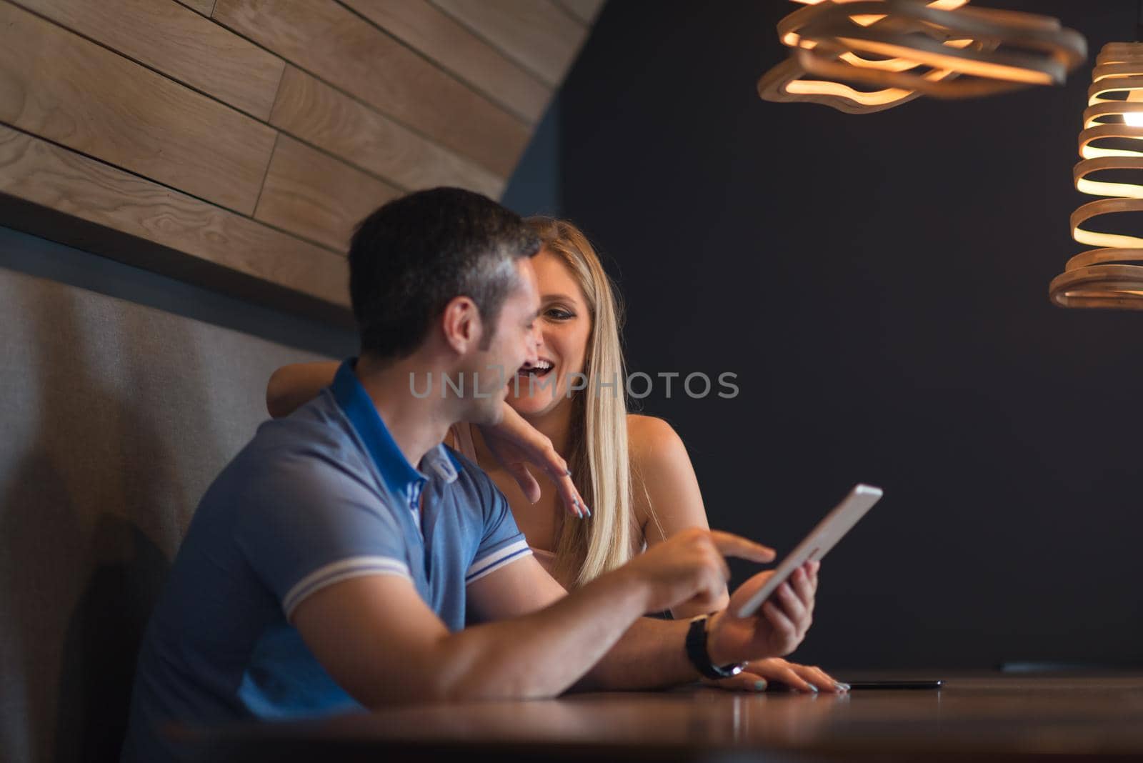 Young couple using tablet computer at luxury home together, looking at screen, smiling.