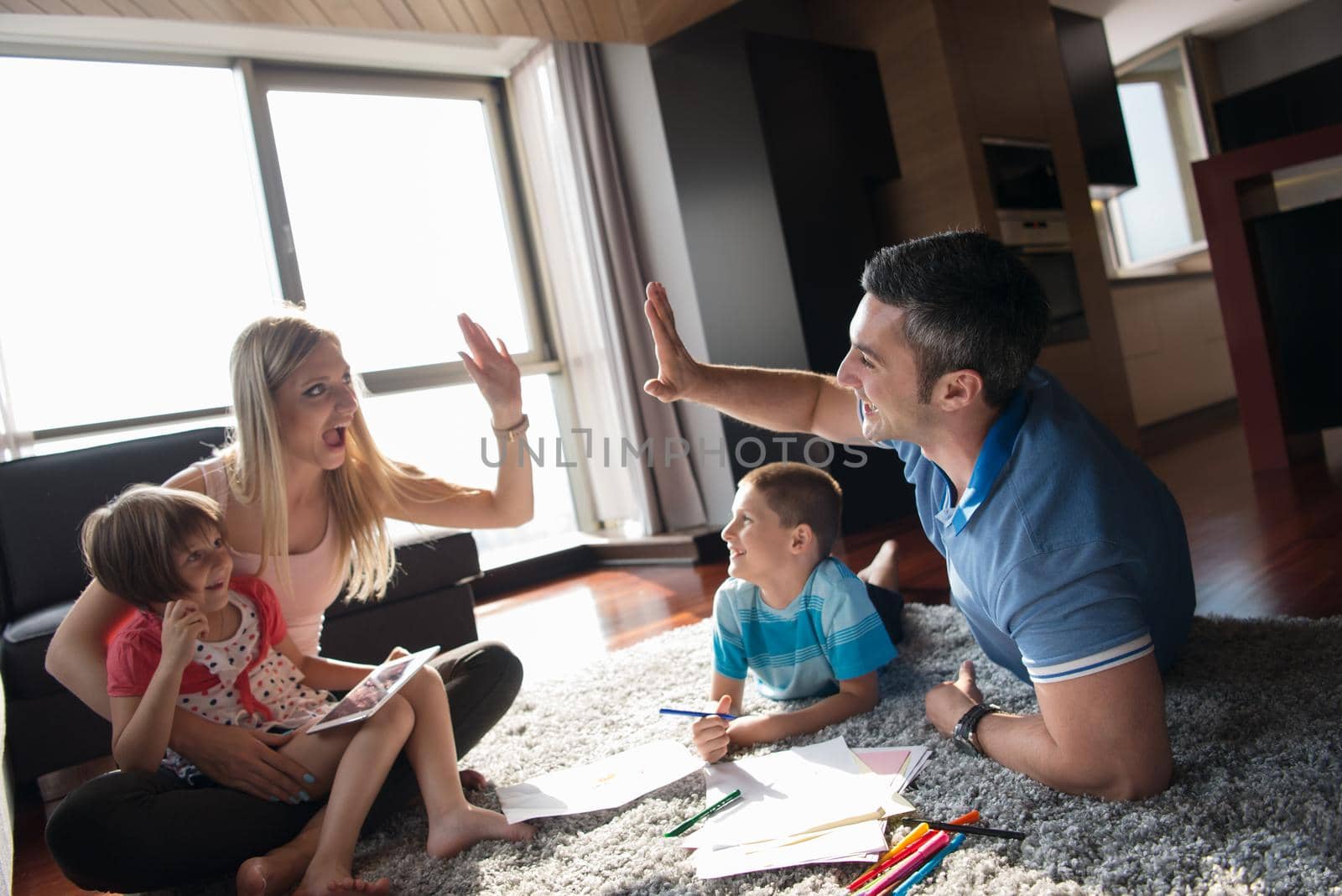 Happy Young Family Playing Together at home on the floor using a tablet and a children's drawing set