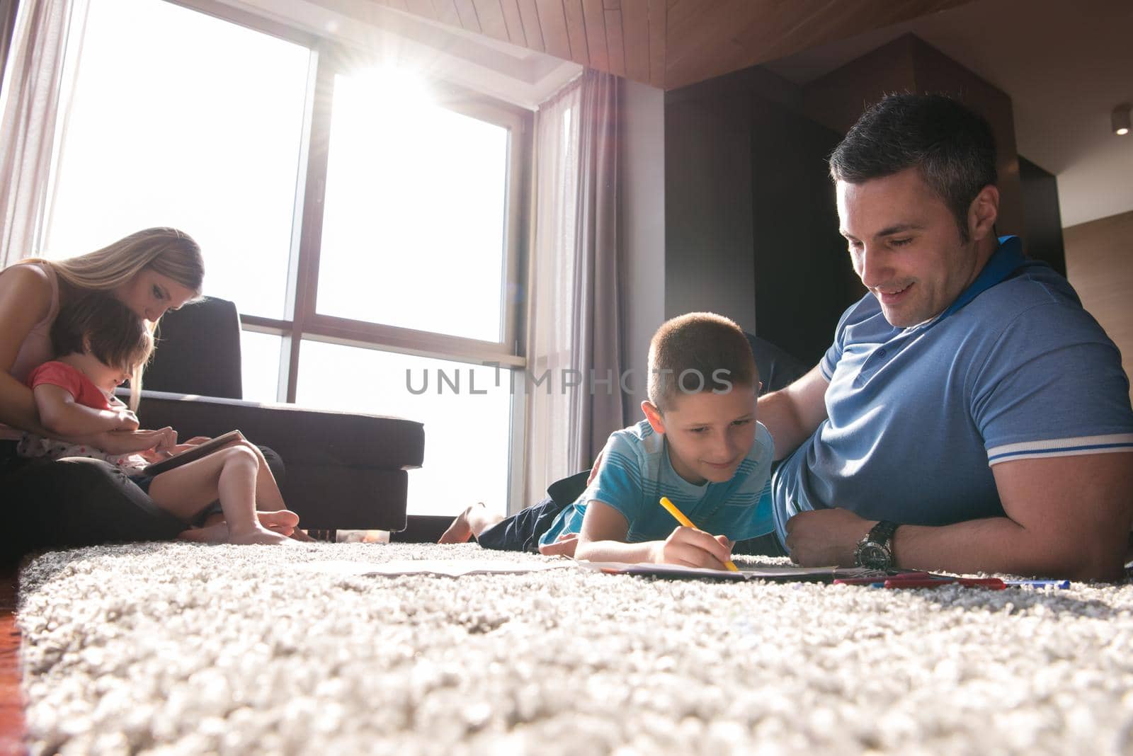 Happy Young Family Playing Together at home on the floor using a tablet and a children's drawing set