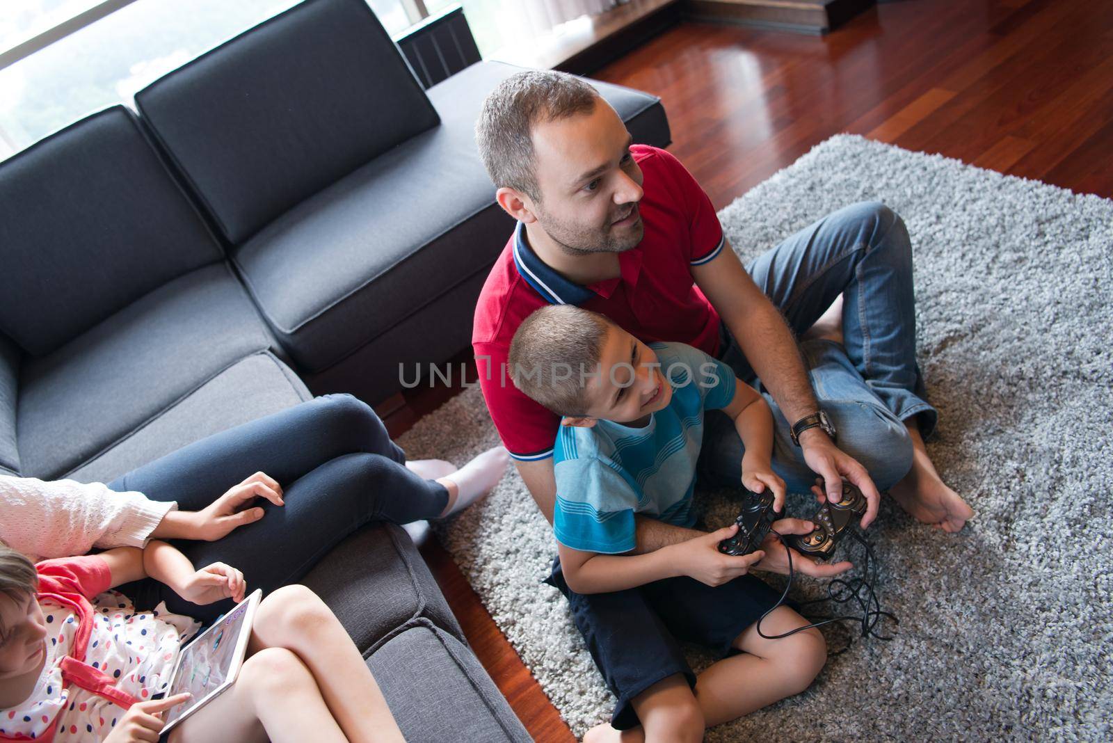 Happy family. Father, mother and children playing a video game Father and son playing video games together on the floor