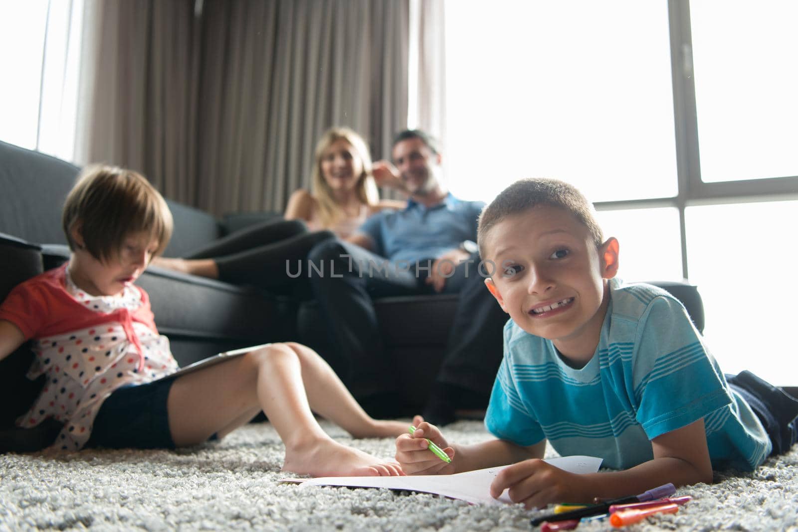 Happy Young Family Playing Together at home on the floor using a tablet and a children's drawing set