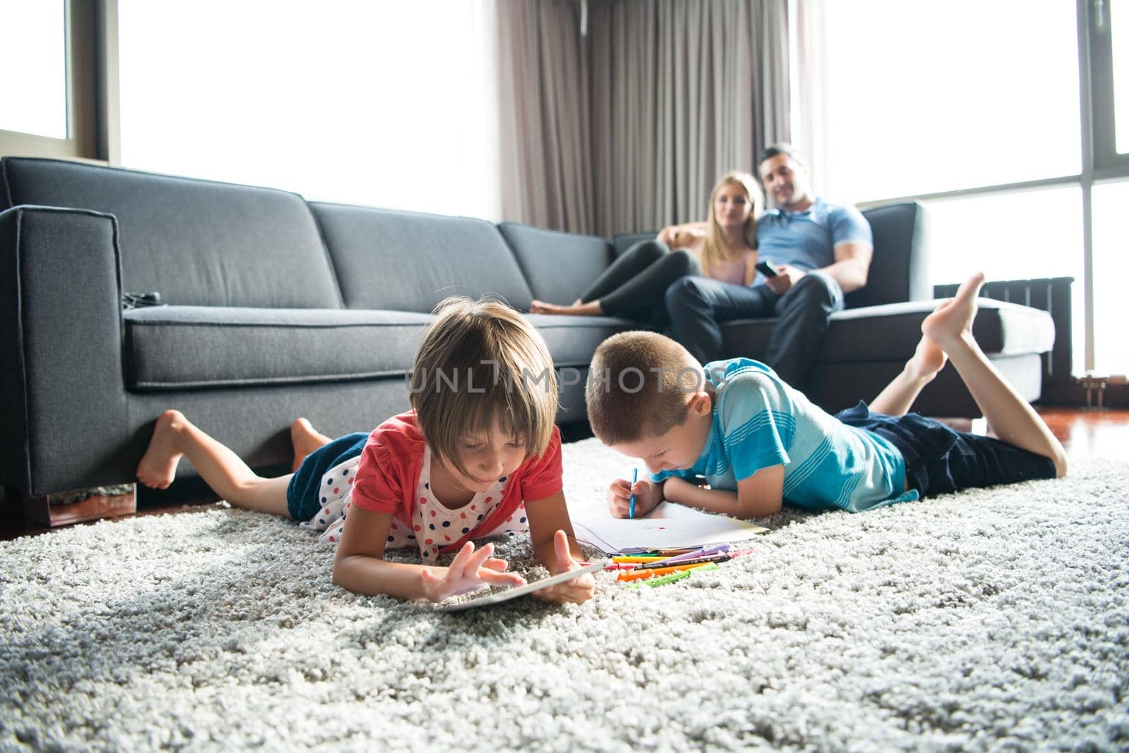 Happy Young Family Playing Together at home on the floor using a tablet and a children's drawing set