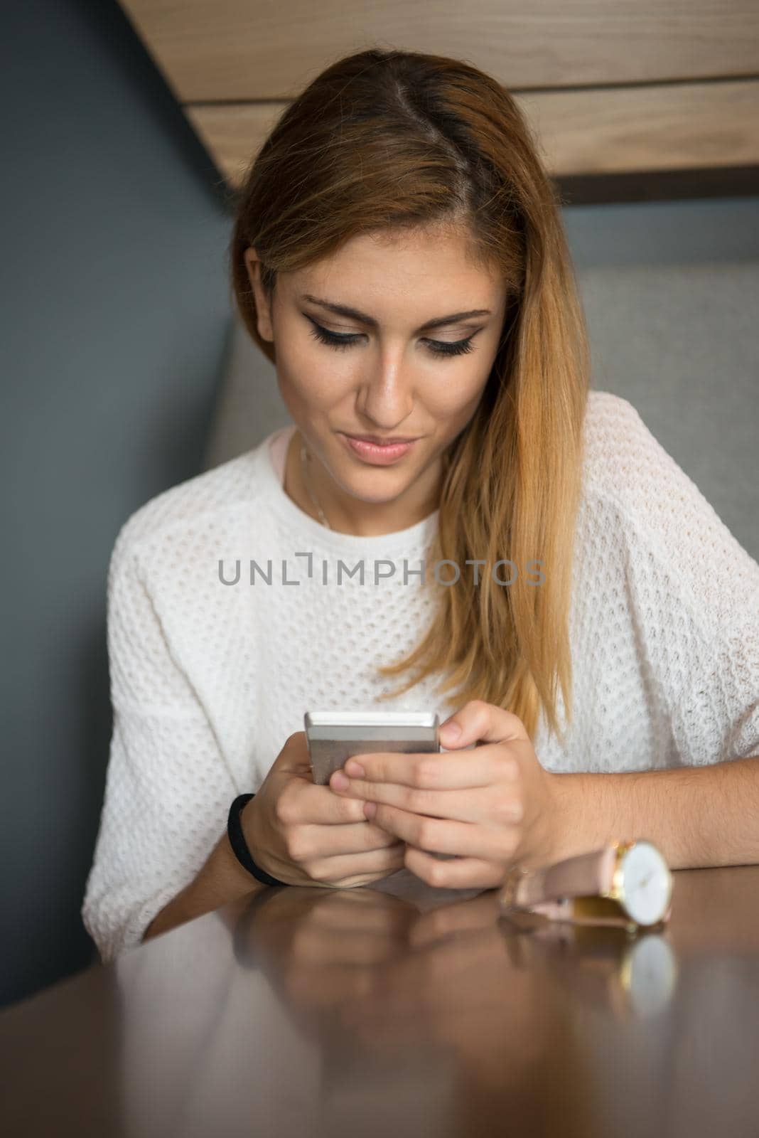 young happy woman sitting at the table and using mobile phone at luxury home