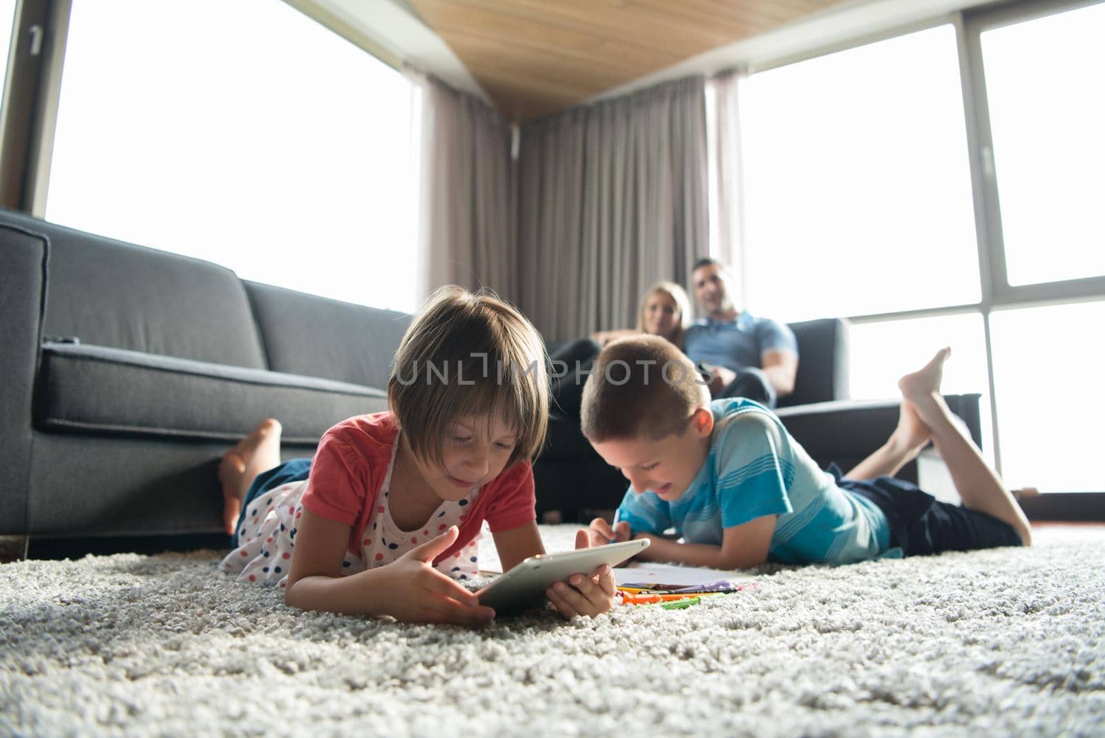 Happy Young Family Playing Together at home on the floor using a tablet and a children's drawing set