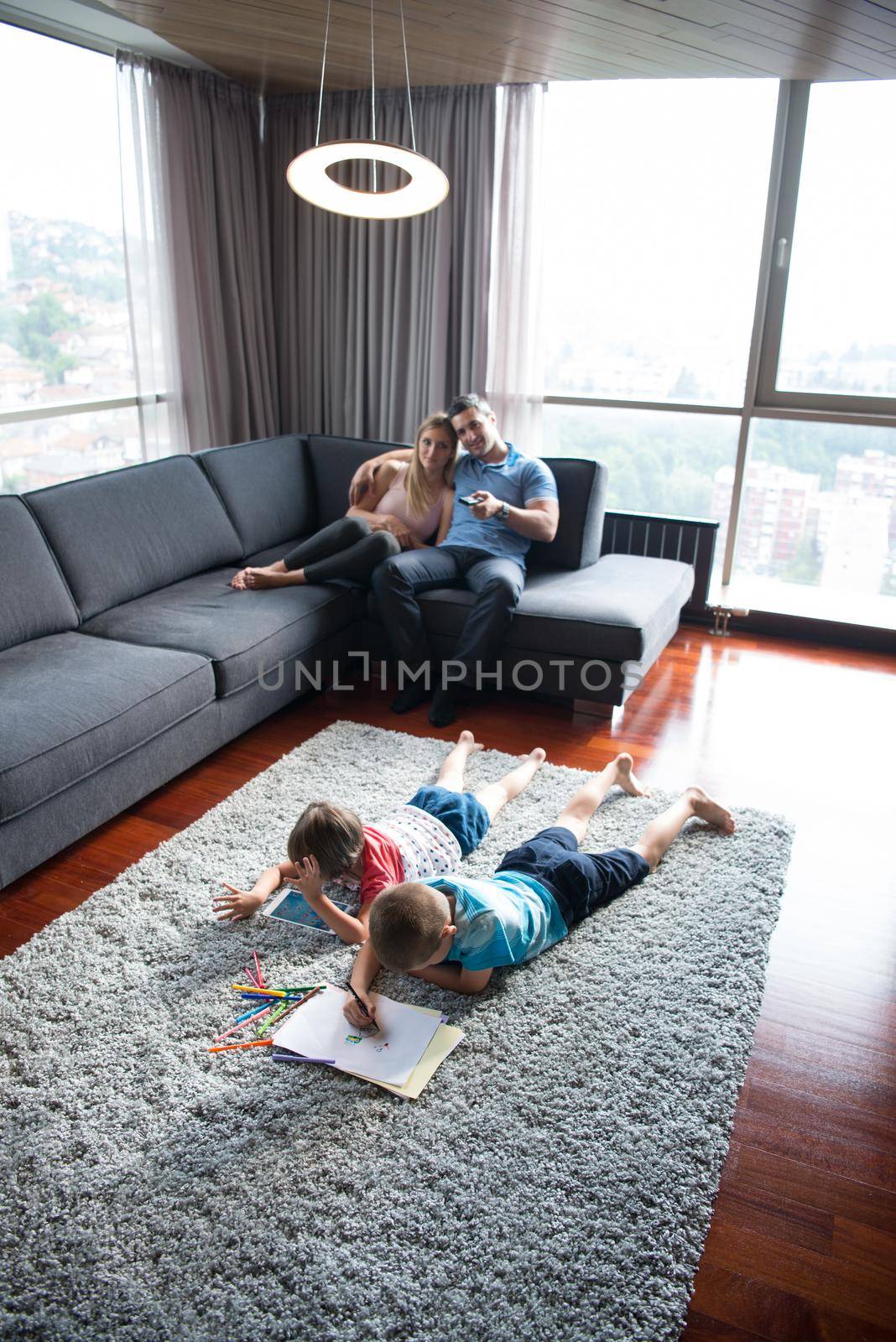 Happy Young Family Playing Together at home on the floor using a tablet and a children's drawing set