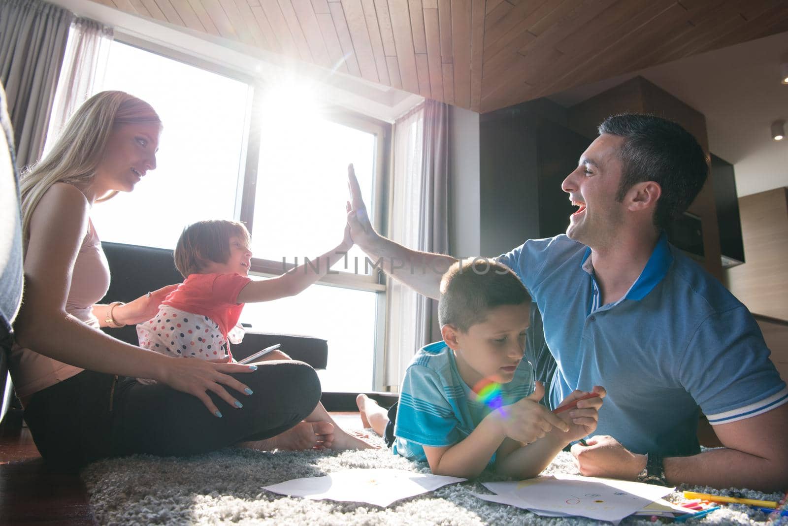 Happy Young Family Playing Together at home on the floor using a tablet and a children's drawing set