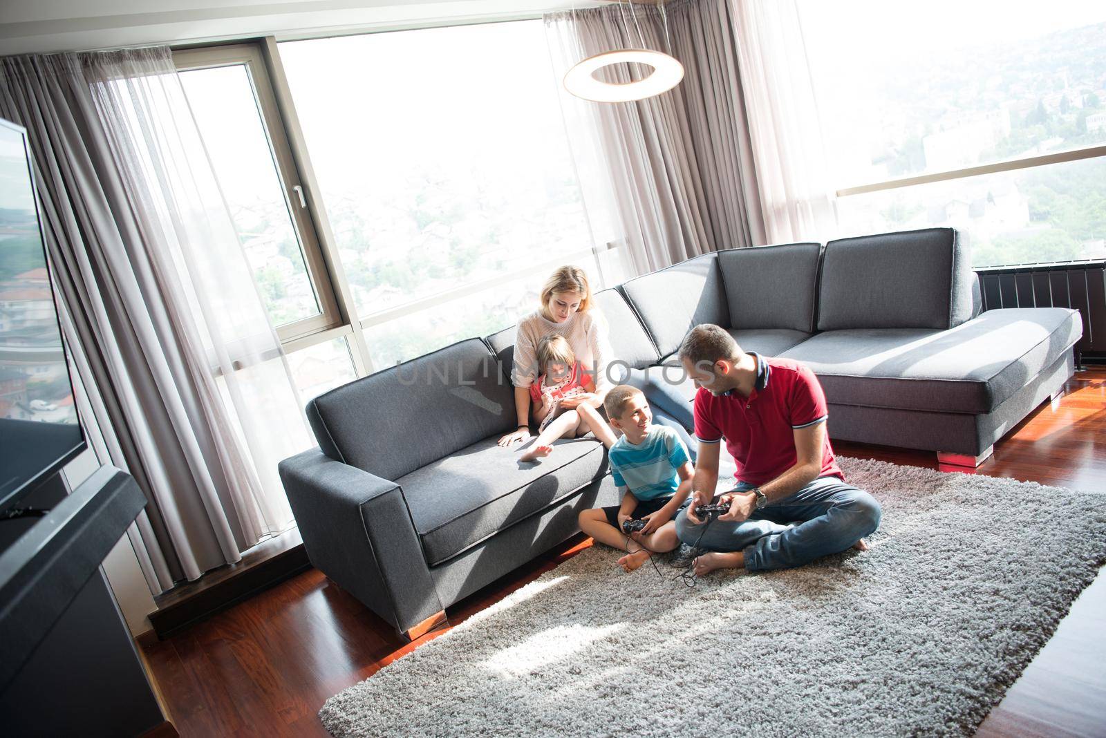 Happy family. Father, mother and children playing a video game Father and son playing video games together on the floor