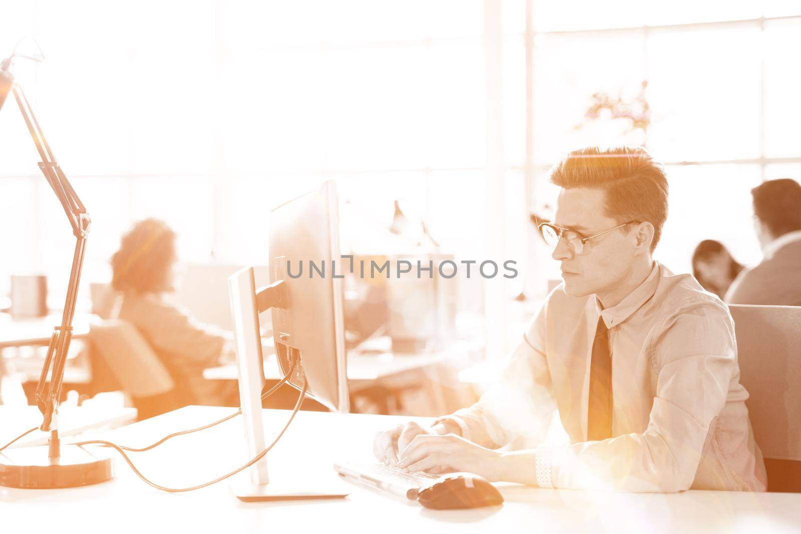 Young businessman programer in big bright office at work using computer