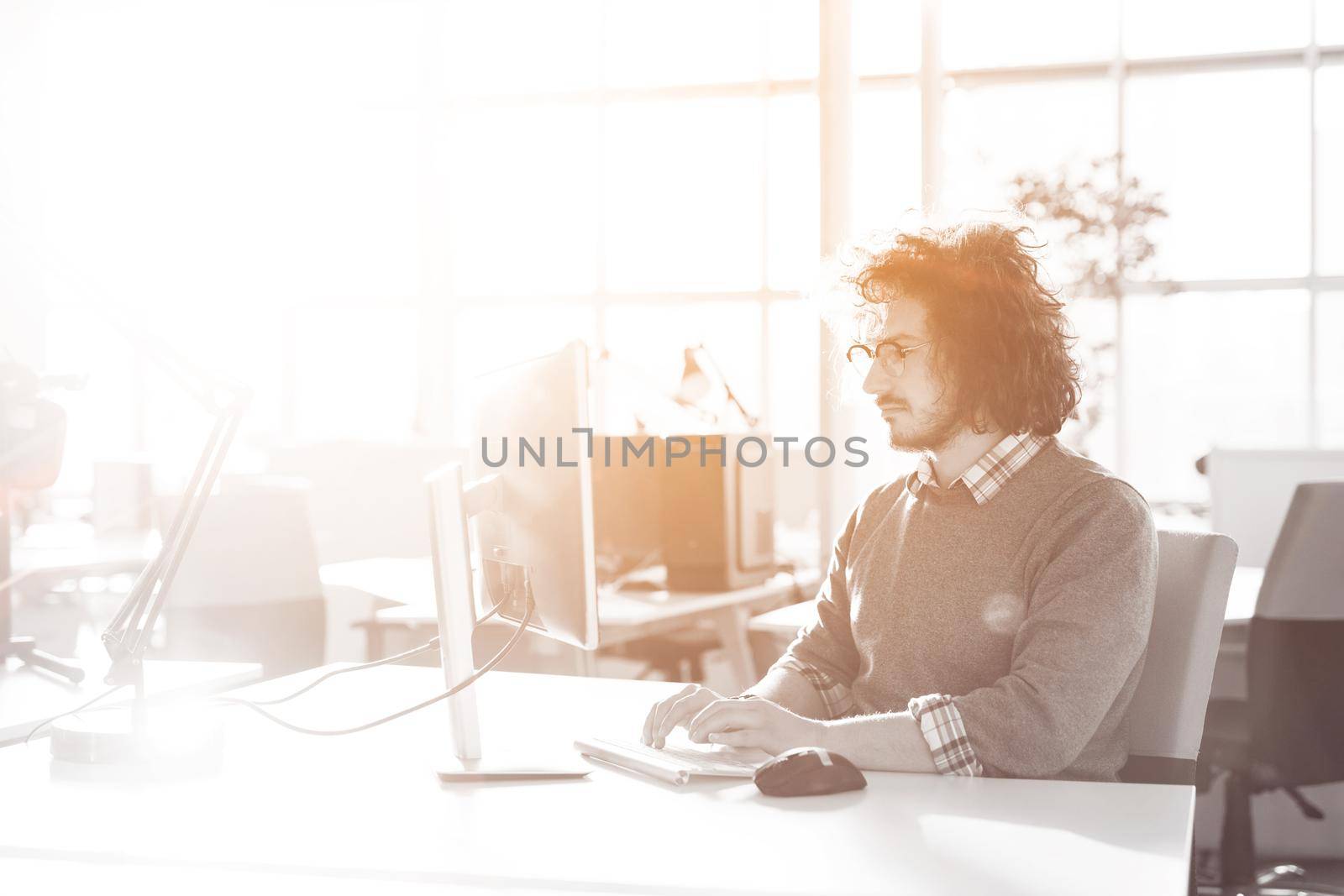 Young businessman programer in big bright office at work using computer