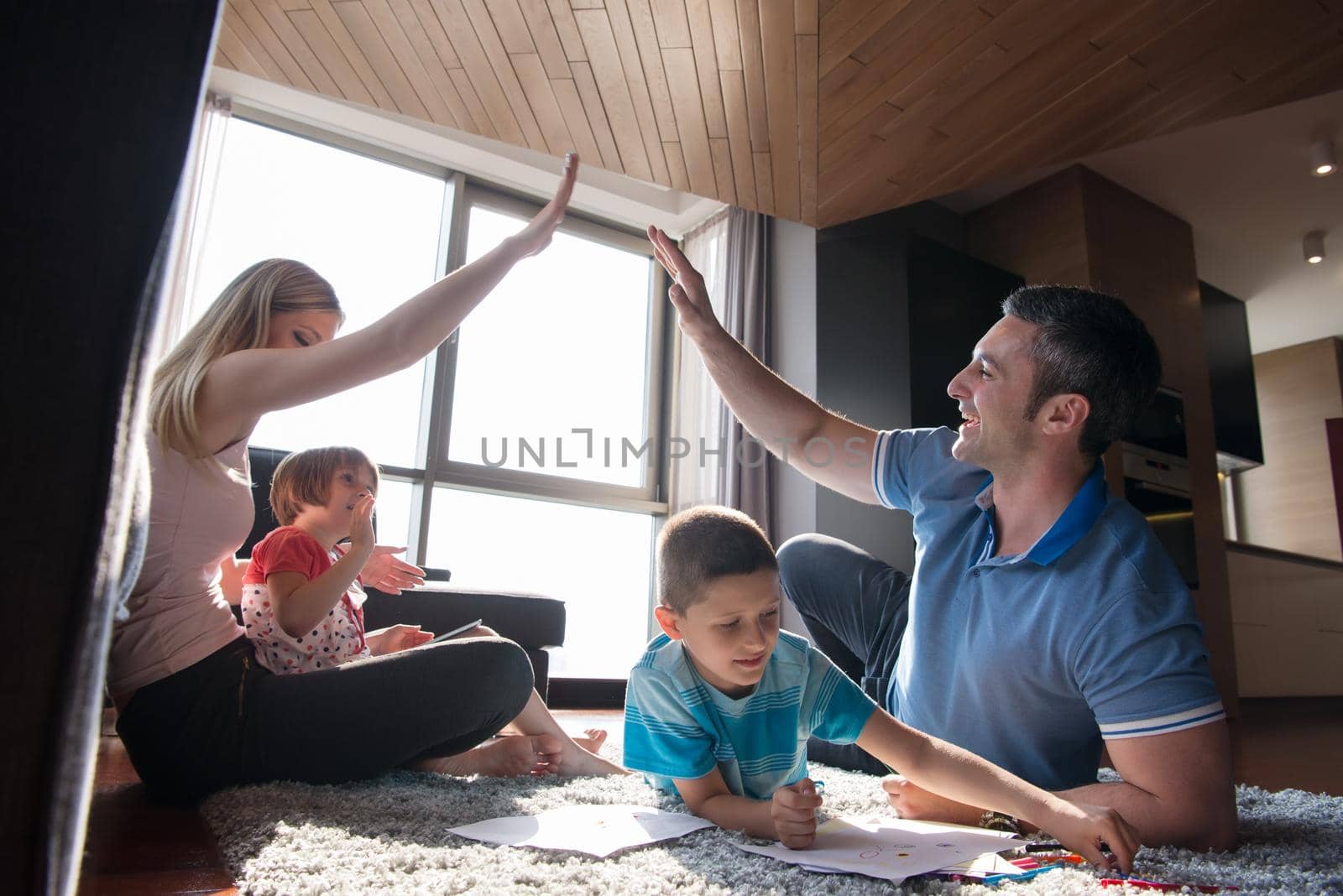 Happy Young Family Playing Together at home on the floor using a tablet and a children's drawing set