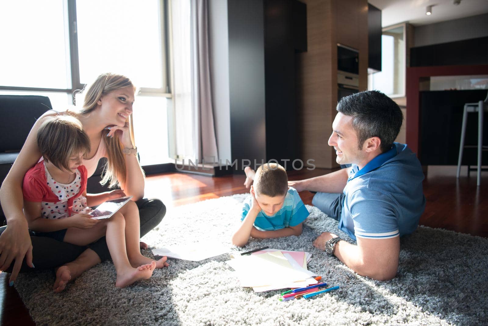 Happy Young Family Playing Together at home on the floor using a tablet and a children's drawing set