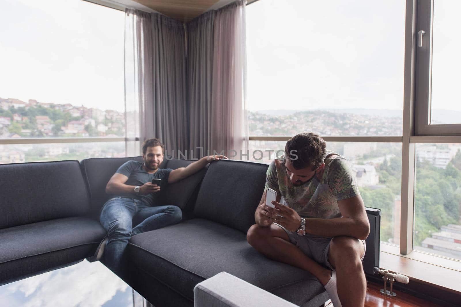 Handsome casual young men using a mobile phones  near the window at home