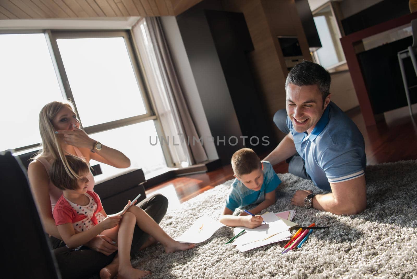 Happy Young Family Playing Together at home on the floor using a tablet and a children's drawing set