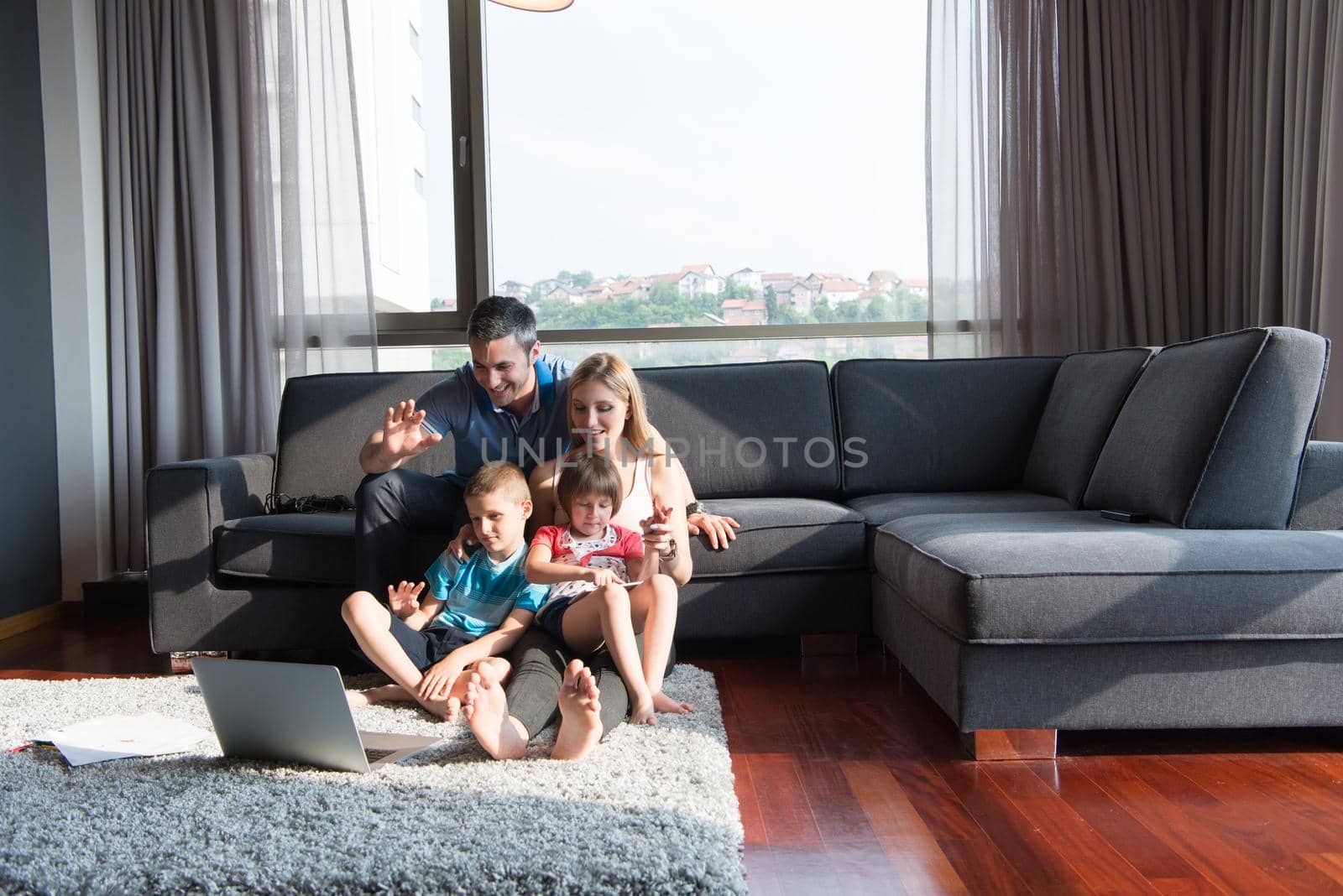 Happy Young Family Playing Together with laptop computer at home sitting on the sofa