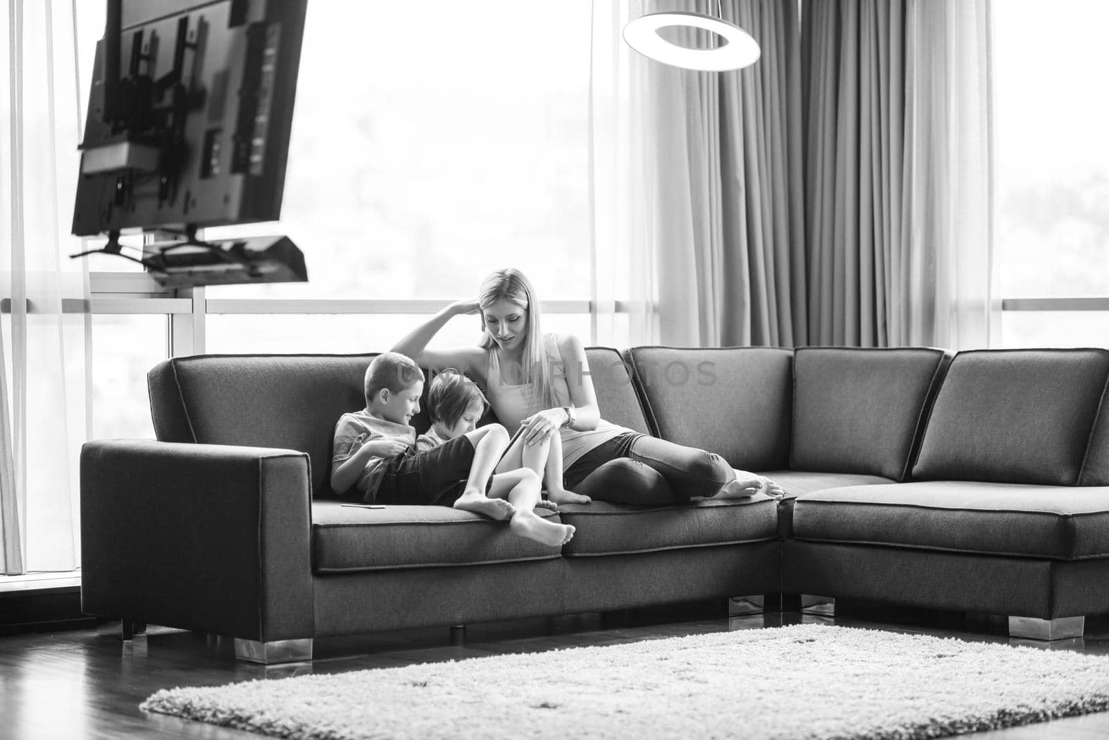 Happy Young Family Playing Together with tablet at home sitting on the sofa