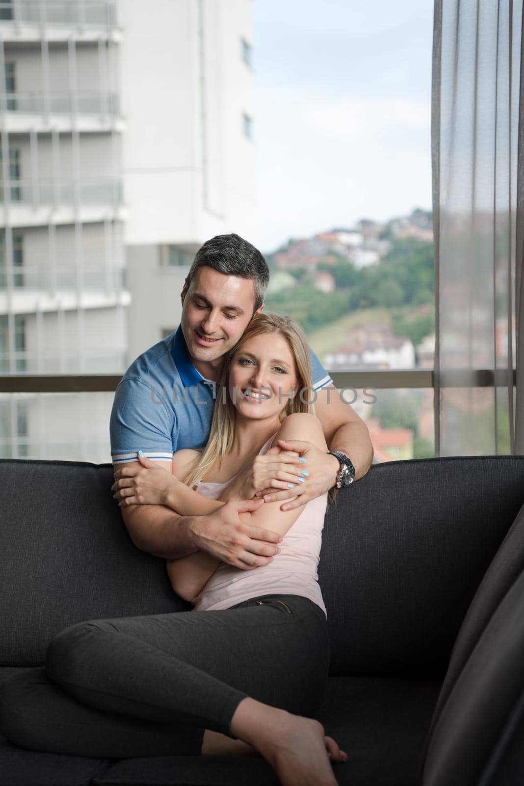 young handsome couple enjoys hugging on the sofa in their luxury home villa