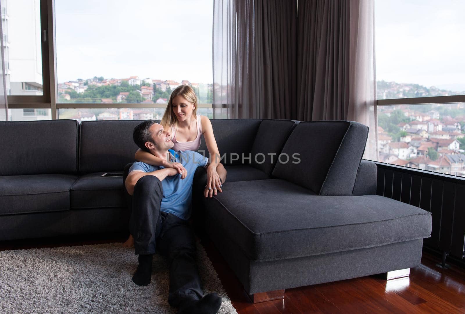 young handsome couple enjoys hugging on the sofa in their luxury home villa