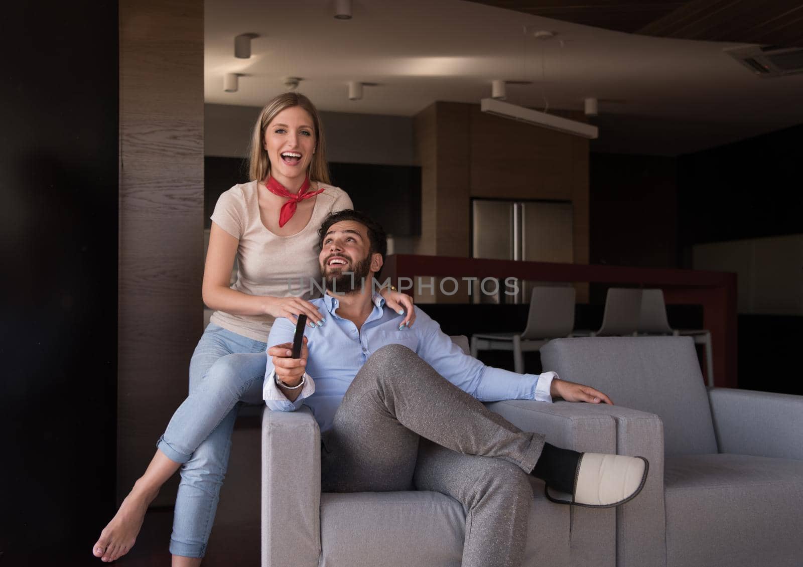 Young couple on the sofa watching television together in their luxury home