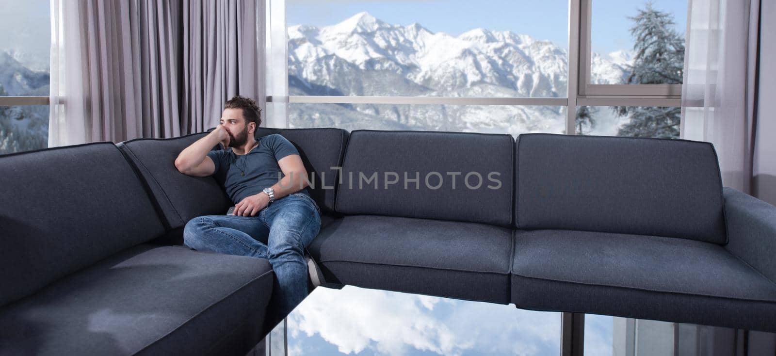 young man sitting on sofa and using a mobile phone  near the window at home