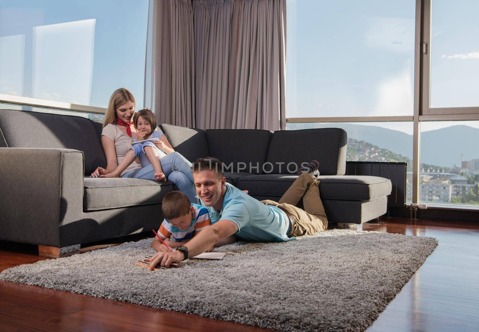 Happy Young Family Playing Together at home on the floor using a tablet and a children's drawing set