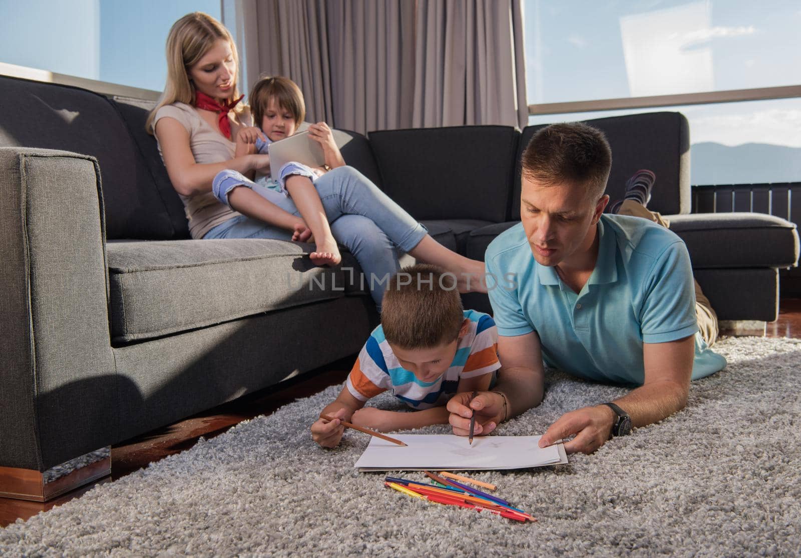 Happy Young Family Playing Together at home on the floor using a tablet and a children's drawing set