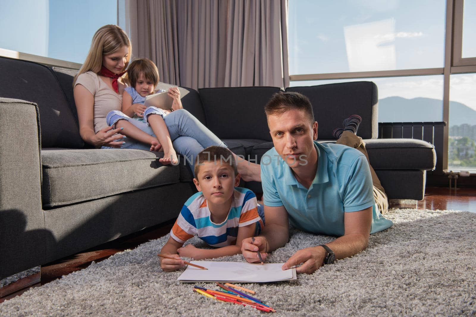 Happy Young Family Playing Together at home on the floor using a tablet and a children's drawing set