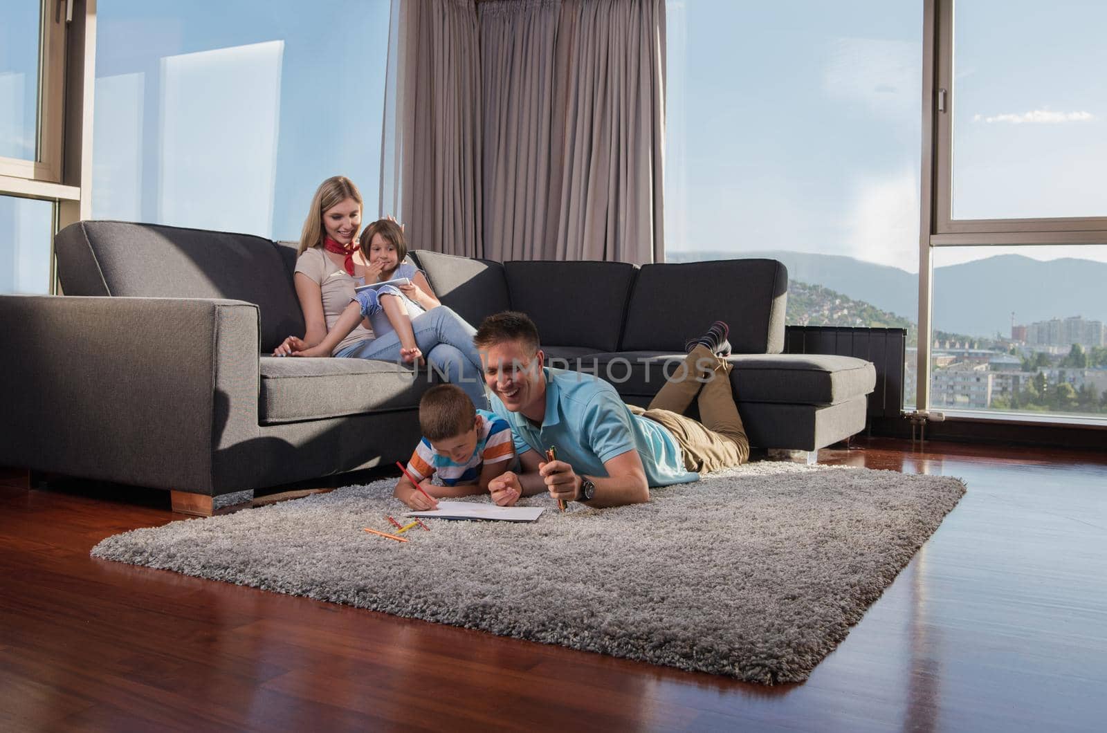 Happy Young Family Playing Together at home on the floor using a tablet and a children's drawing set