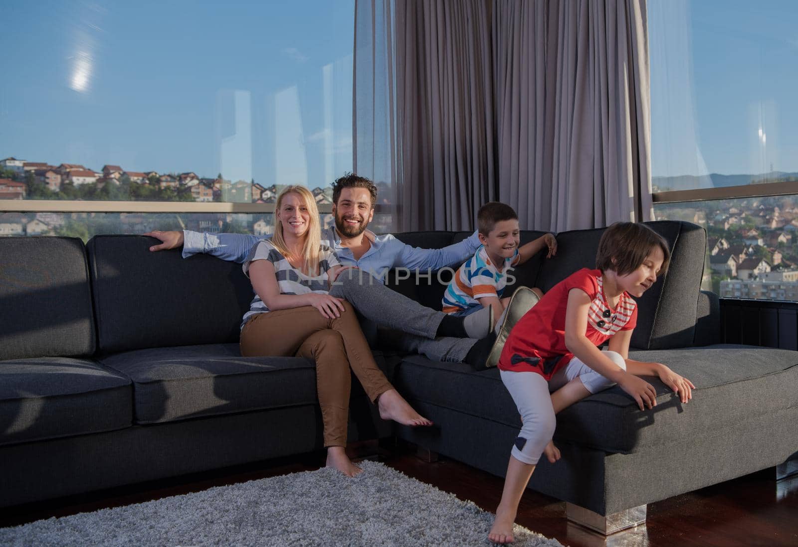 happy couple spending time with kids using tablet computer on sofa at home