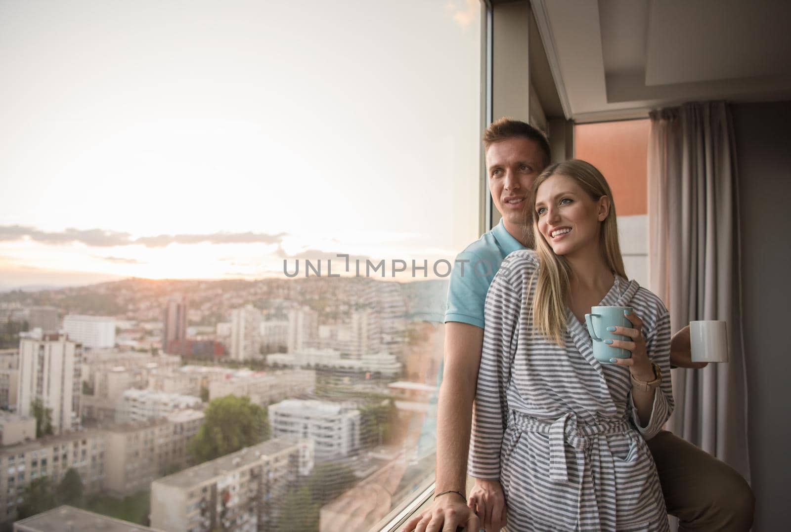 young couple enjoying evening coffee by the window by dotshock