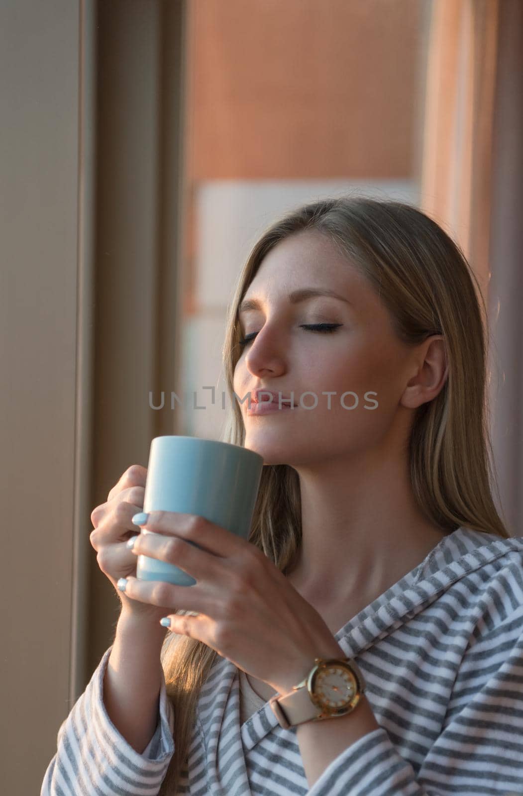 young woman enjoying evening coffee by the window by dotshock
