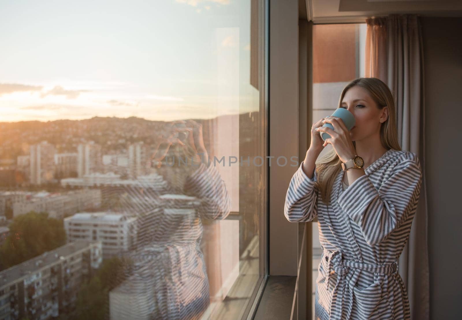young woman enjoying evening coffee by the window by dotshock