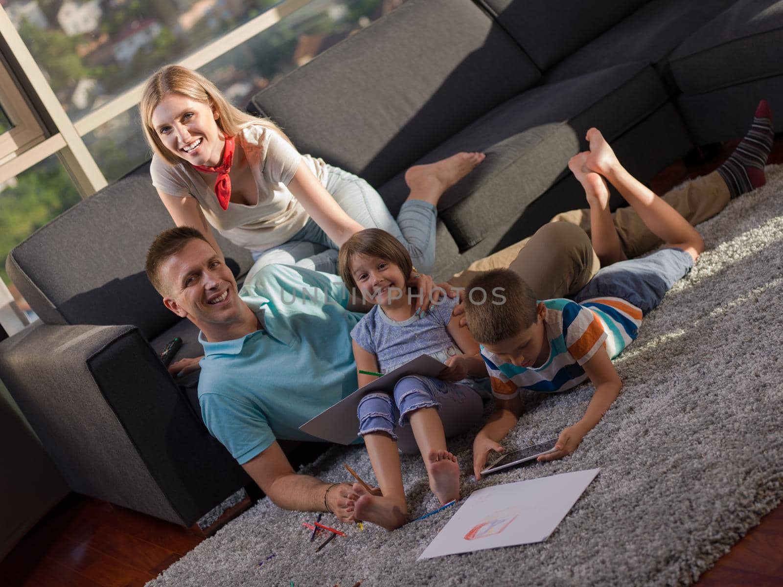 Happy Young Family Playing Together at home using a tablet and a children's drawing set