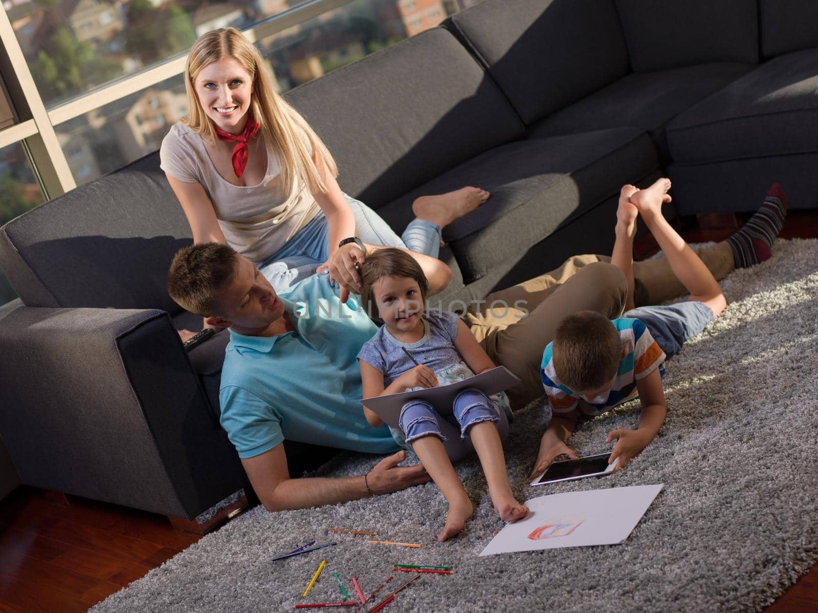 Happy Young Family Playing Together at home using a tablet and a children's drawing set